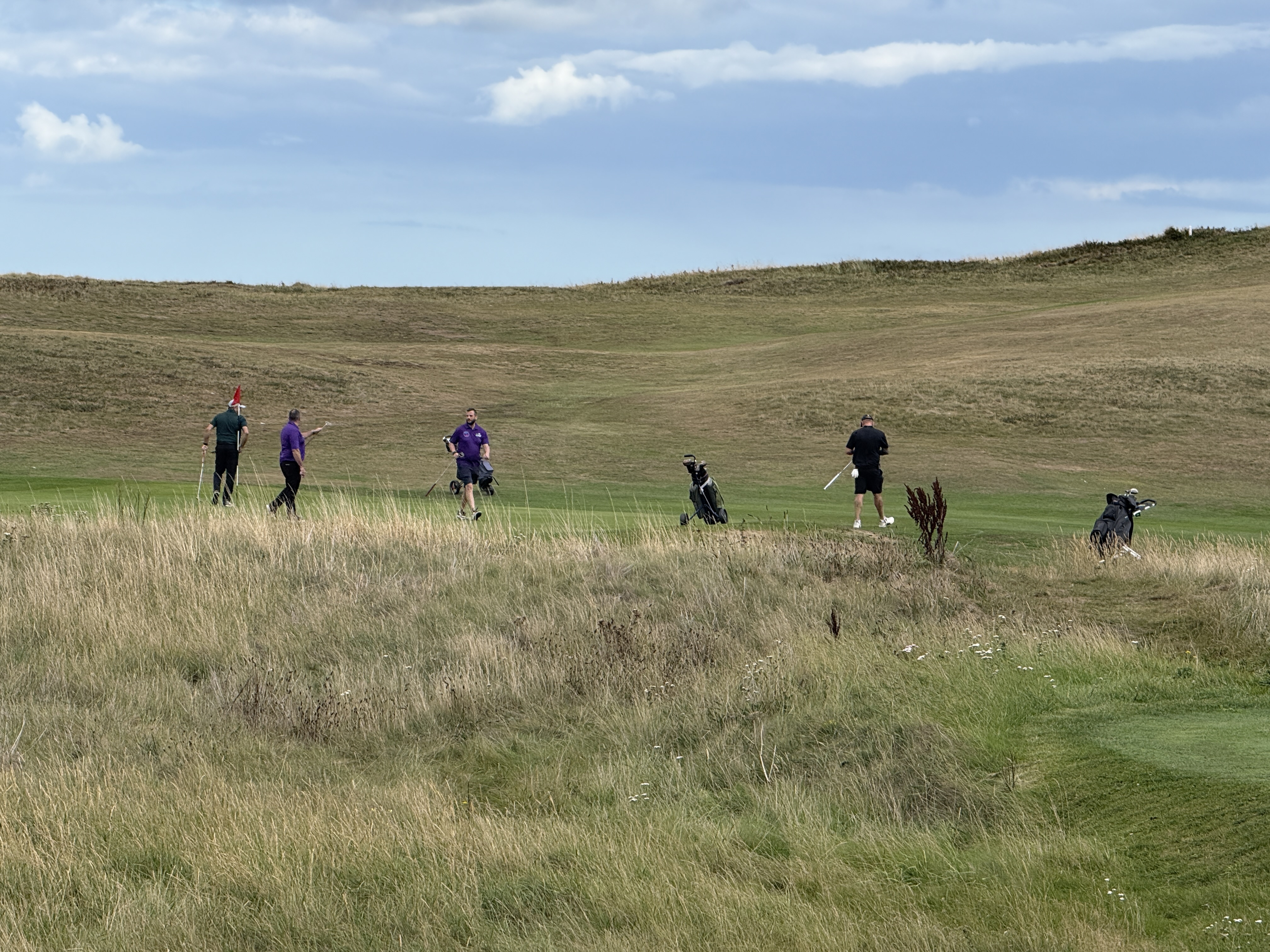 Team teeing off with the sea in the background — Miles For Men Golf Day